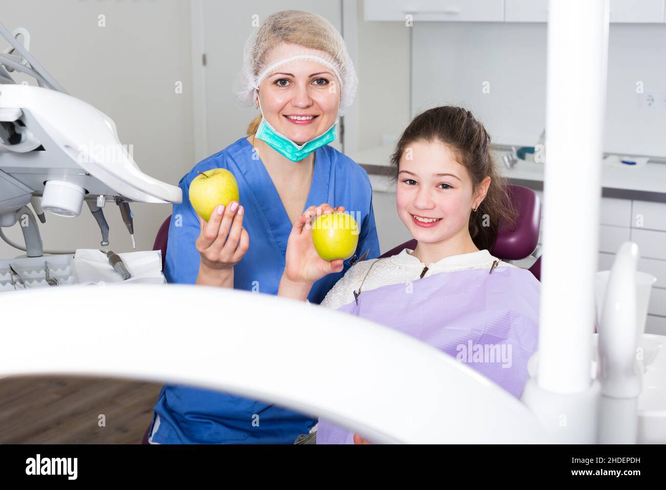 Happy girl with female dentist showing apples Stock Photo Alamy