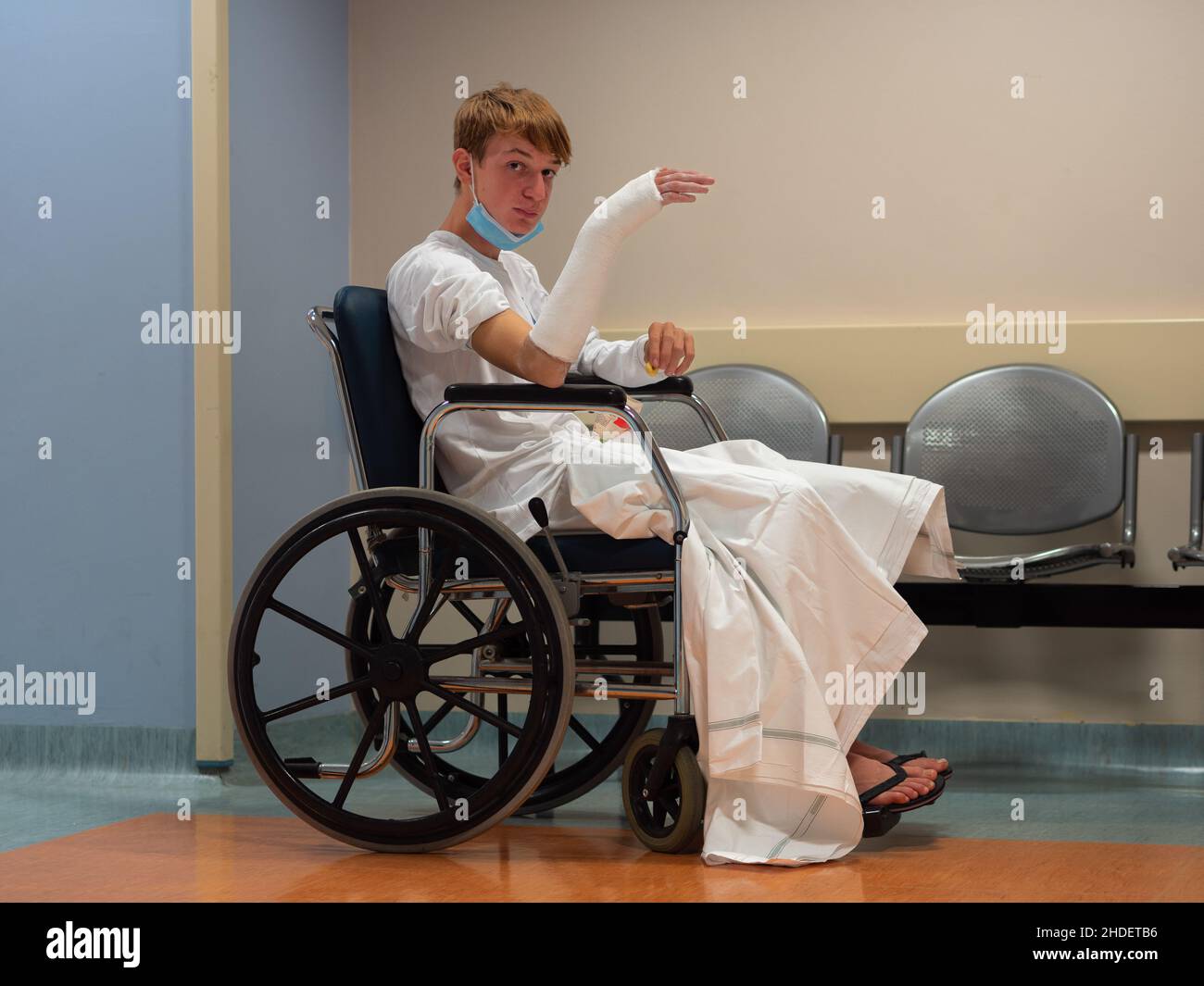 Teenage Boy Sitting in Wheelchair in Hospital with Arm and Wrist in Cast Shortly after Injury. Stock Photo