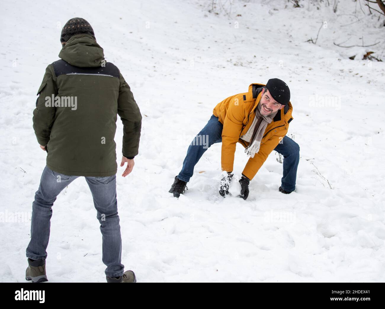 Father and son playing snowball fight on park on cold winter day Stock Photo