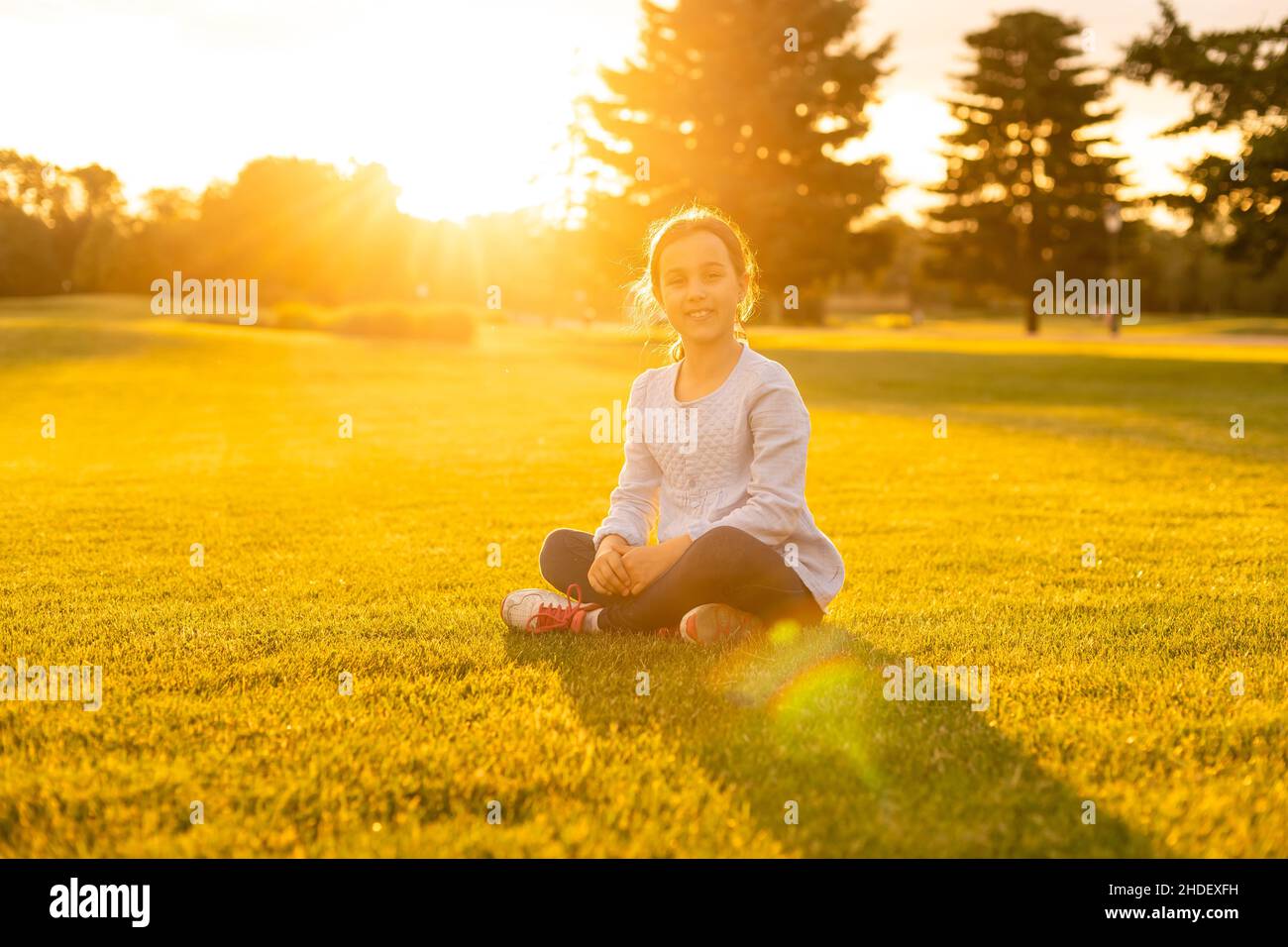 little girl sitting on the grass in the park Stock Photo - Alamy