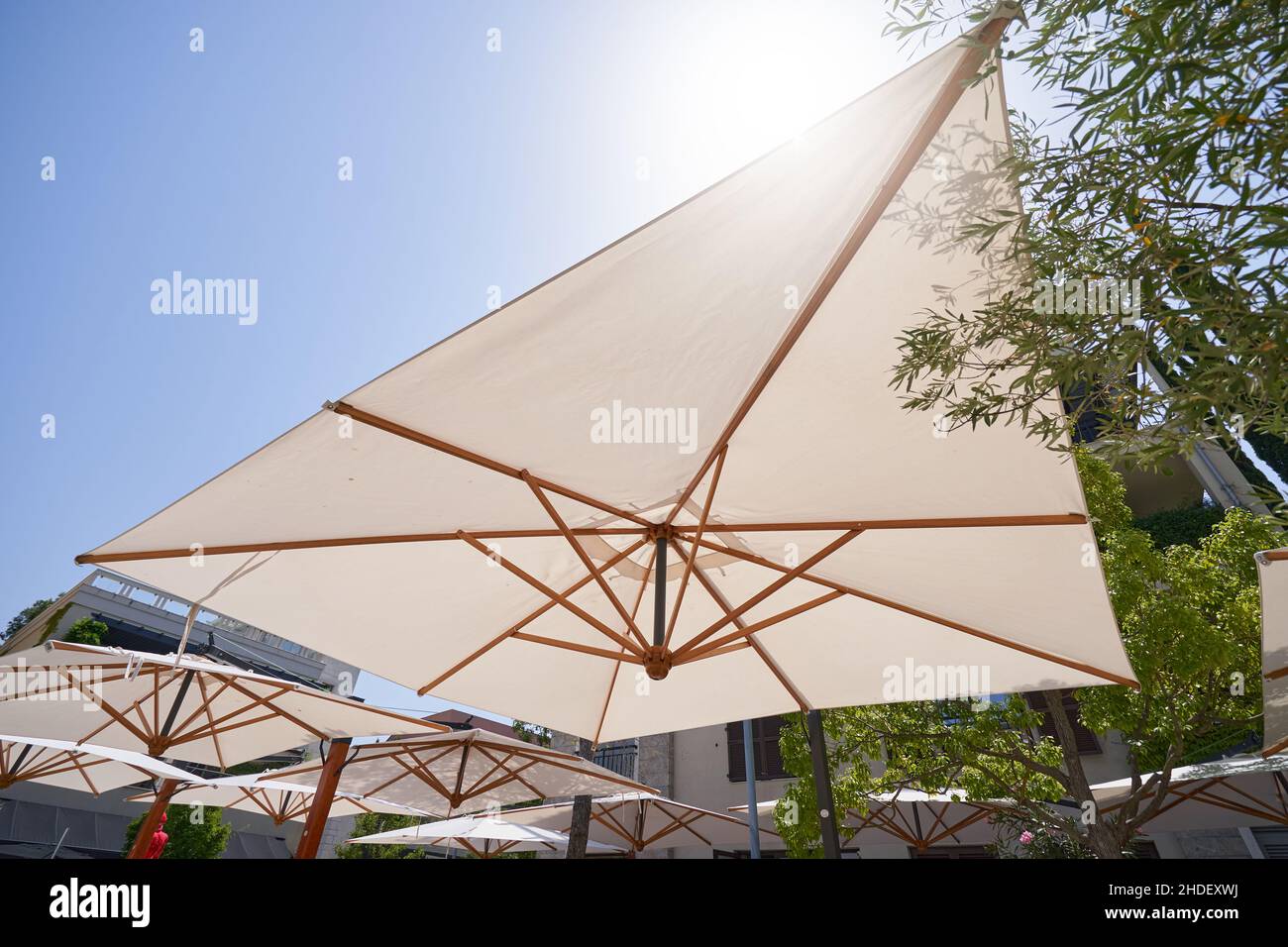 A large umbrella protects from the sun in a street cafe. Stock Photo