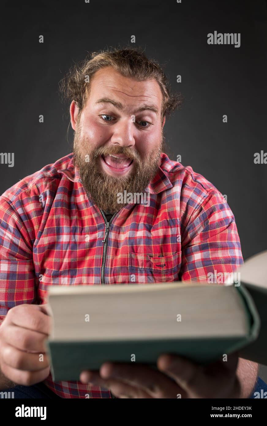 Adult student feeling surprised while reading a book Stock Photo Alamy