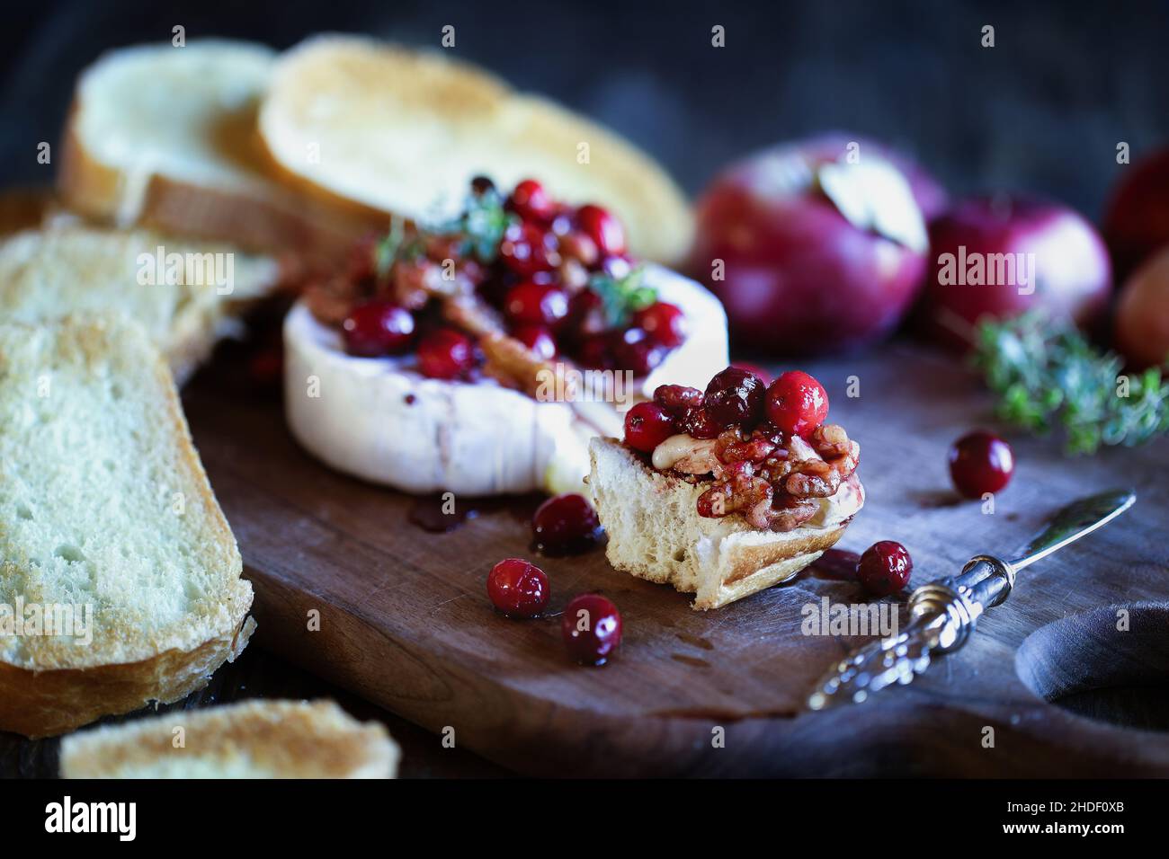 Toasted French bread with baked Camembert Brie cheese and cranberry, honey, balsamic vinegar and nut relish. Selective focus with extreme blurred fore Stock Photo