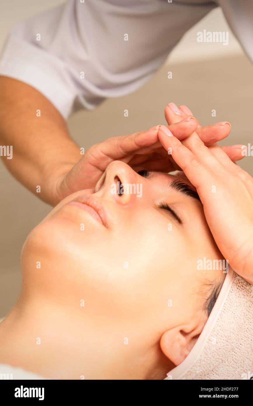 Beautiful young caucasian woman receiving a head massage in a beauty clinic, close up Stock Photo