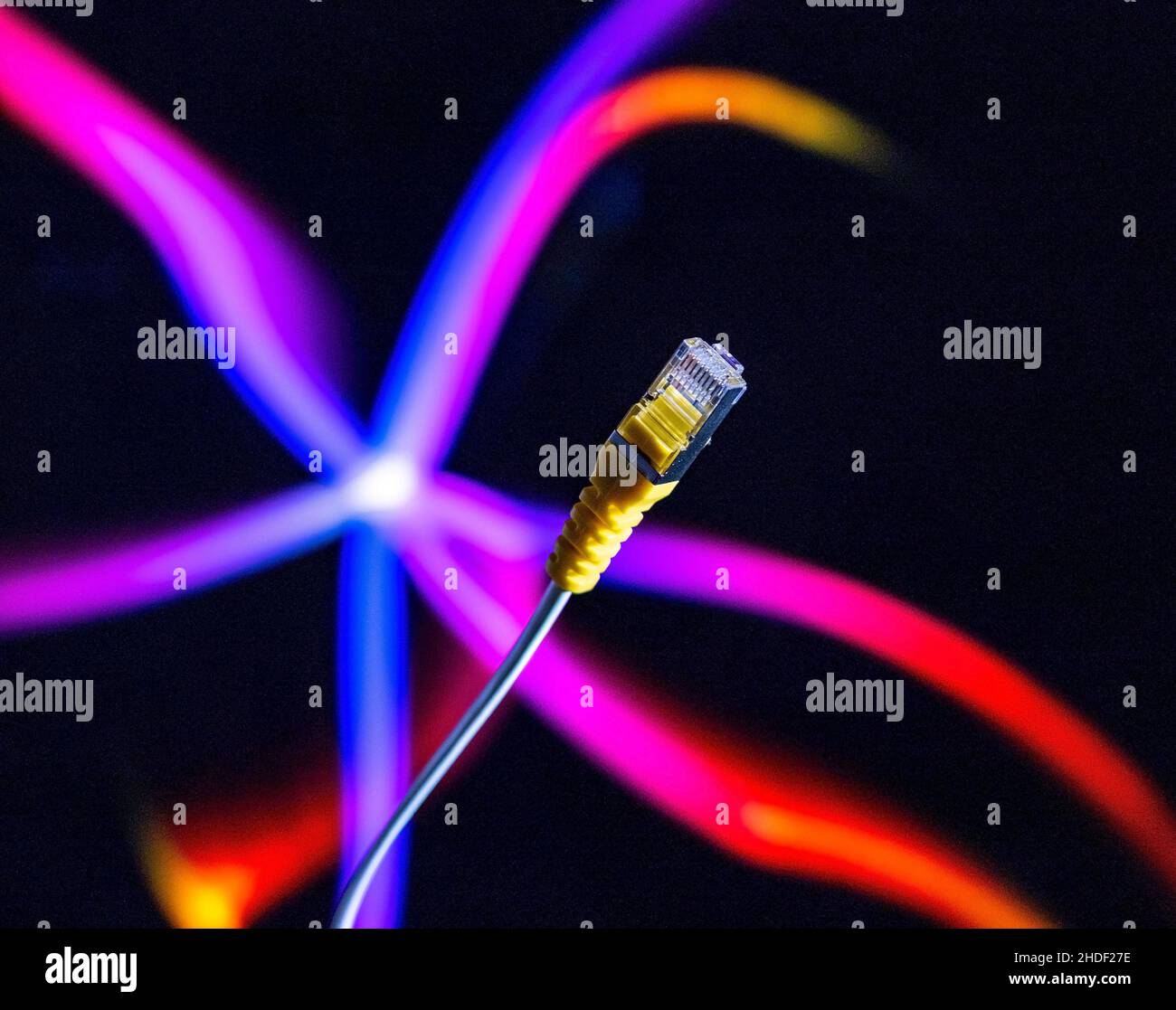 Internet cable and yellow ethernet connector in close up against a colourful background. Stock Photo