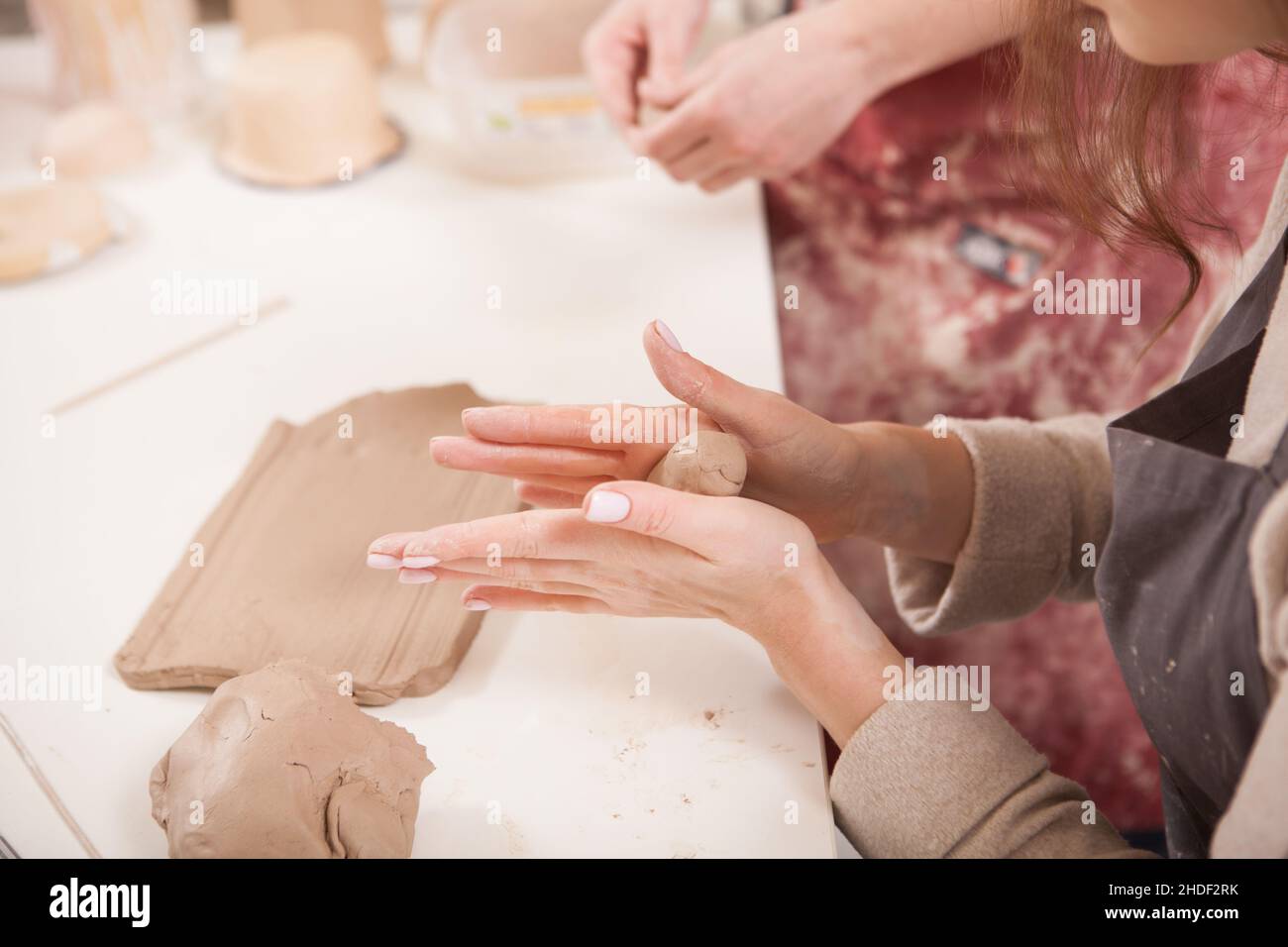 Cropped close up of a woman shaping piece of clay in her hands at