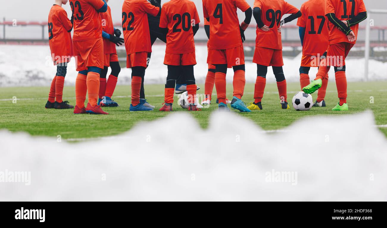 Football Players on Winter Soccer Training Camp. Young Boys Standing in a Circle With Coach on Grass Pitch. Snow Covering Grass Football Field Stock Photo