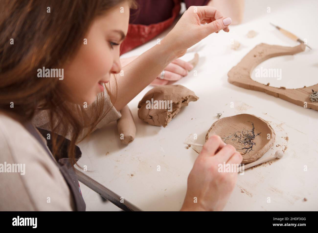 Close up of a woman making ceramic plate at clay workshop Stock Photo