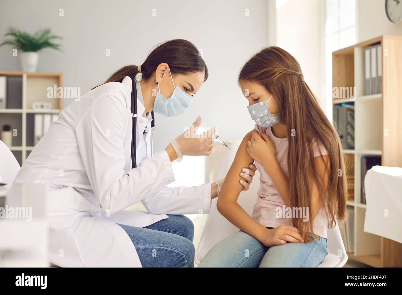 Nurse or doctor at a vaccination center giving a shot to a little girl ...