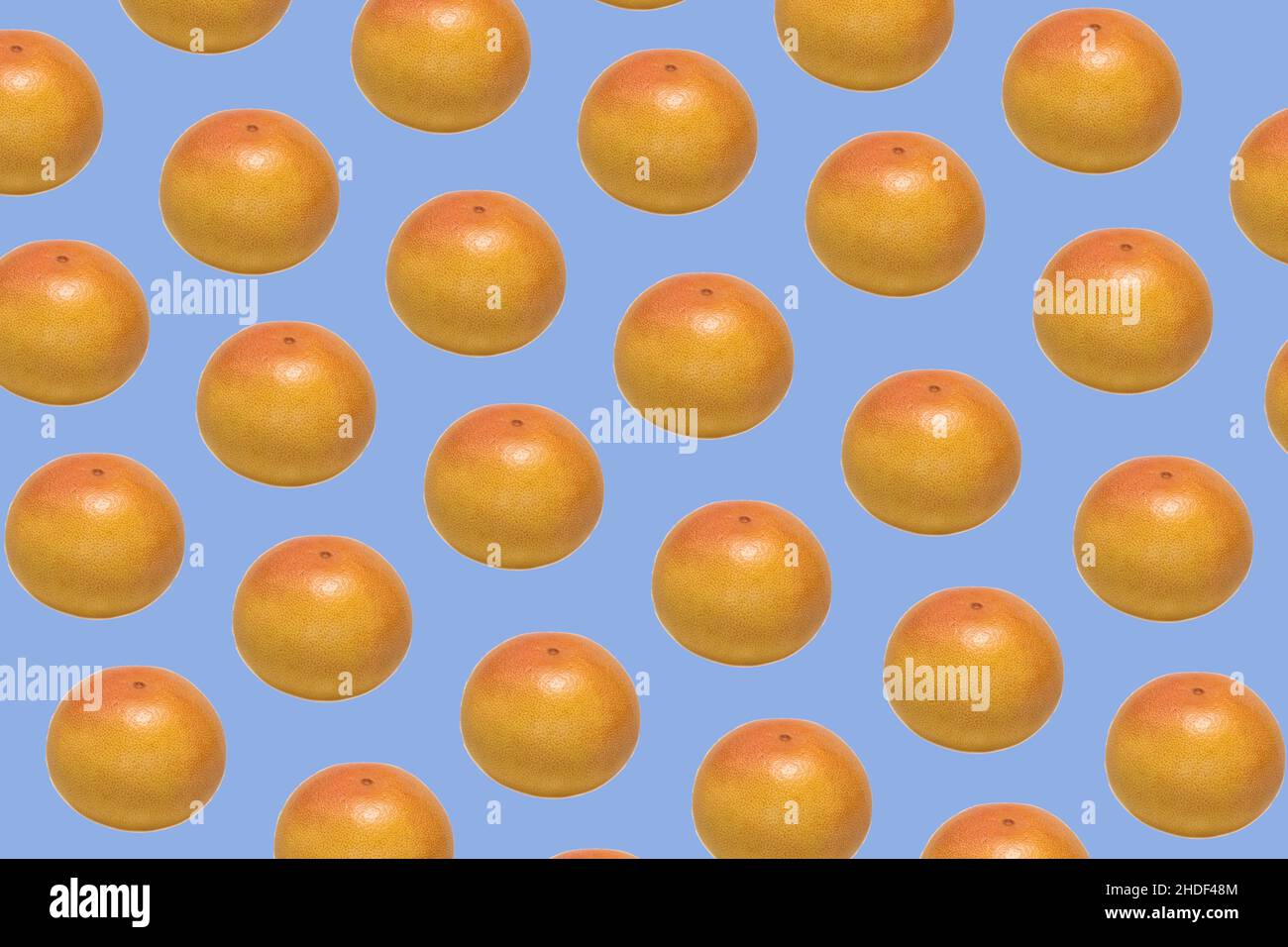 Pattern made of whole ripe ruby grapefruit on blue background Stock Photo