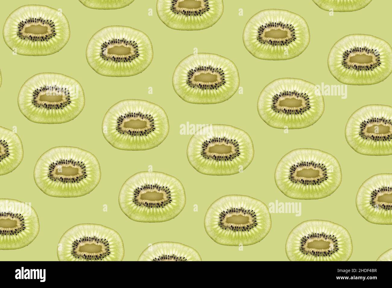 Pattern made of backlit kiwi fruit slices on green background Stock Photo