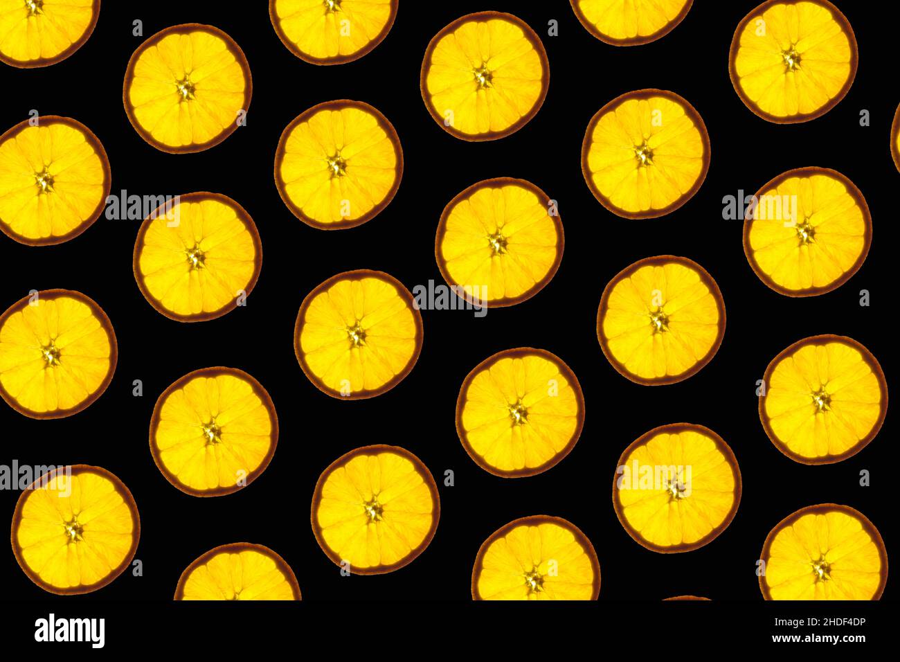 Pattern made of backlit orange slices on black background Stock Photo ...