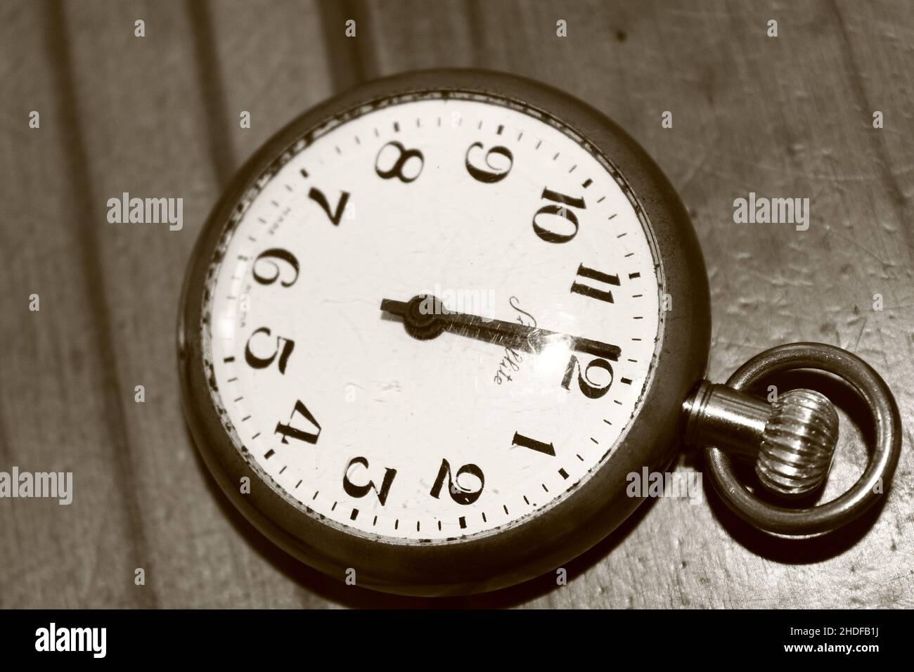 Monochrome picture of old fashioned pocket watch against wooden background Stock Photo