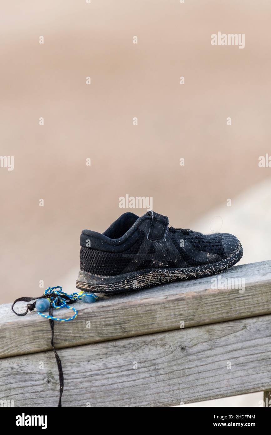 A small beach shoe left behind on a wooden railing. Stock Photo