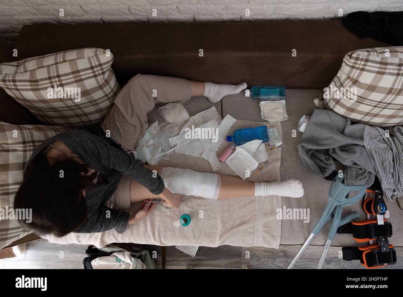 Above shoot with a young woman changing her bandage at home after an