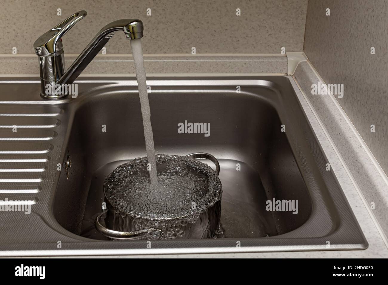 tap water is poured into the pan in the sink Stock Photo