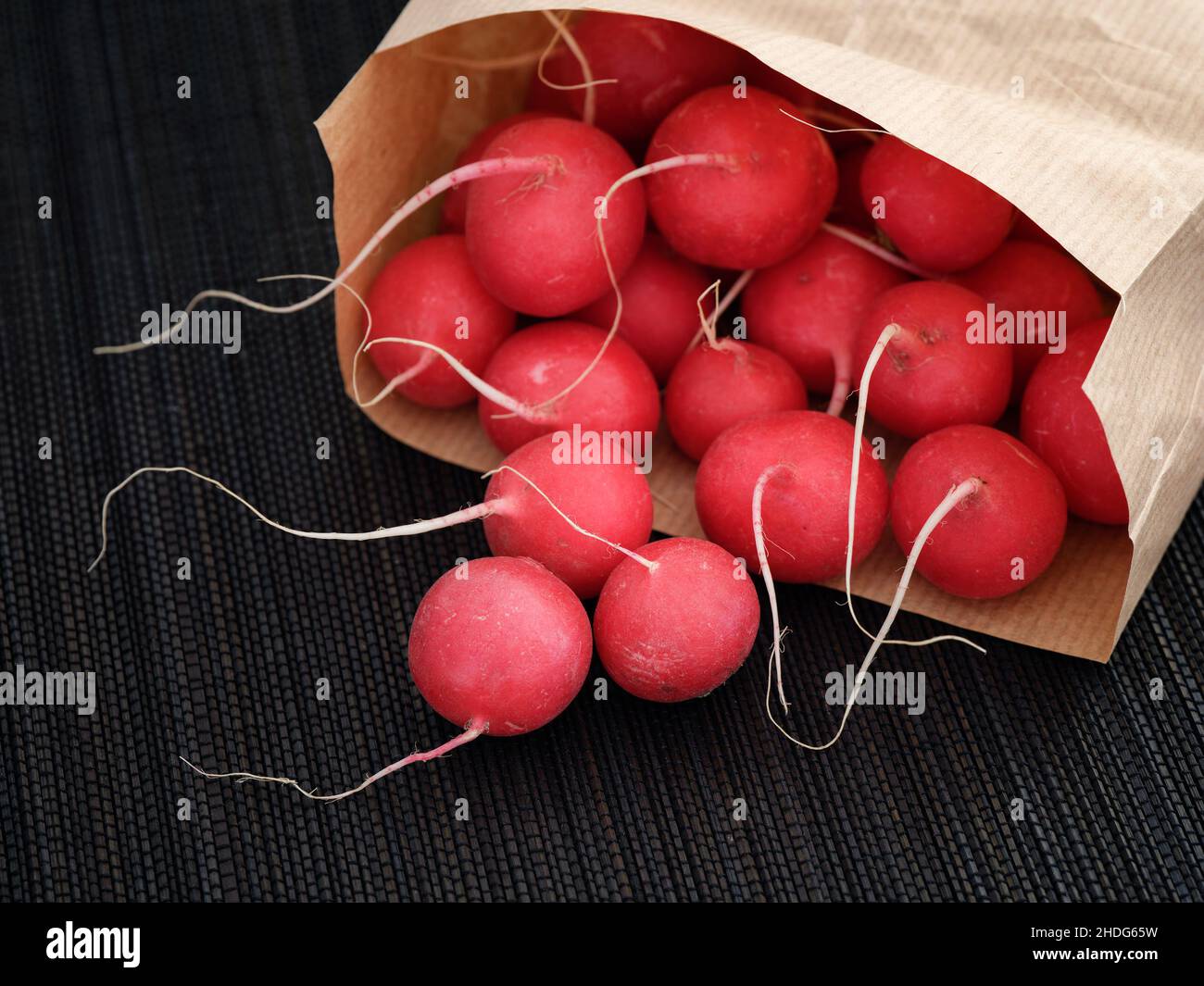 Red radishes in a paper bag. Low key. Close up. Stock Photo