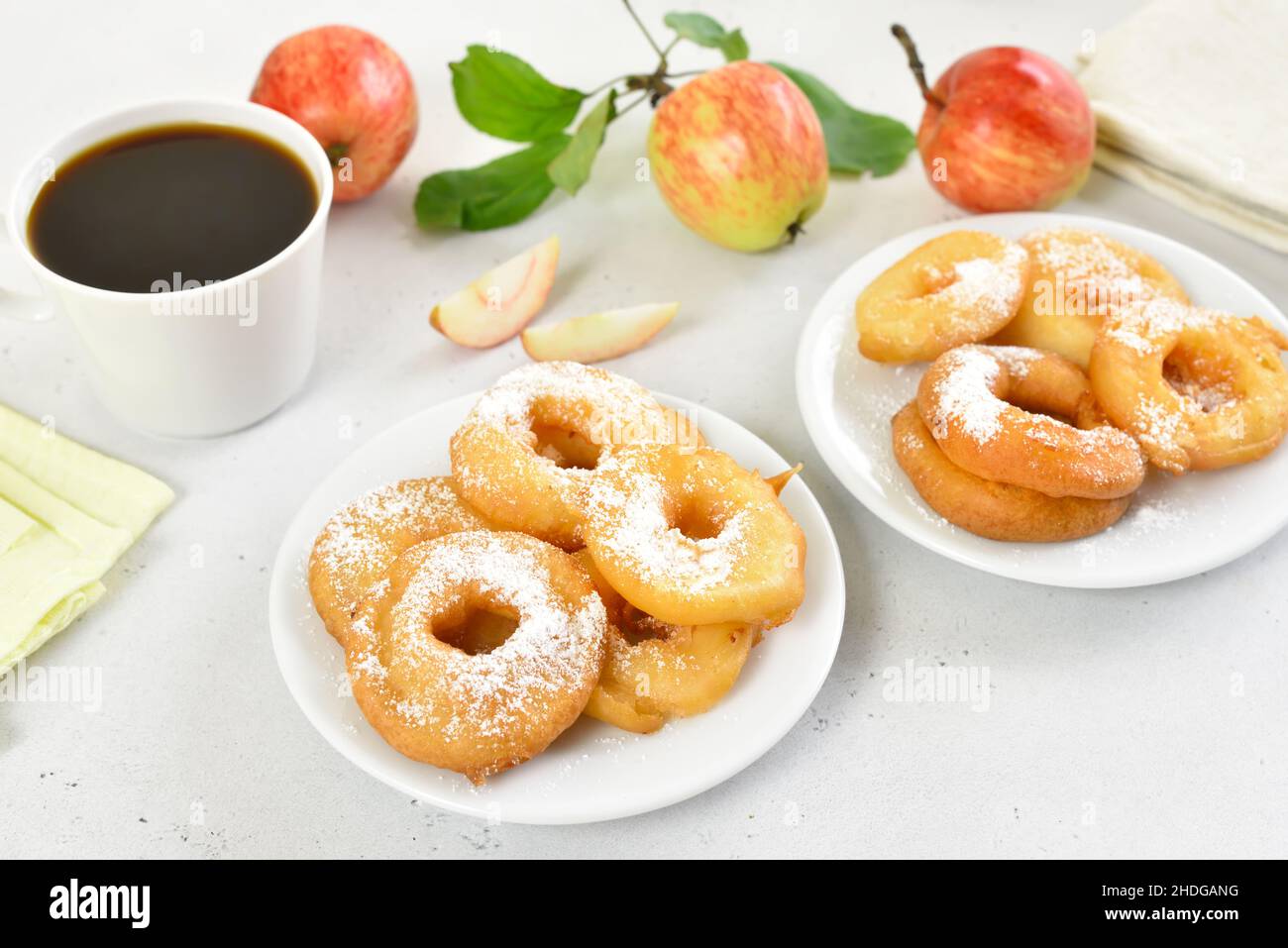 Apple rings on white plate, cup of black coffee on light stone background Stock Photo