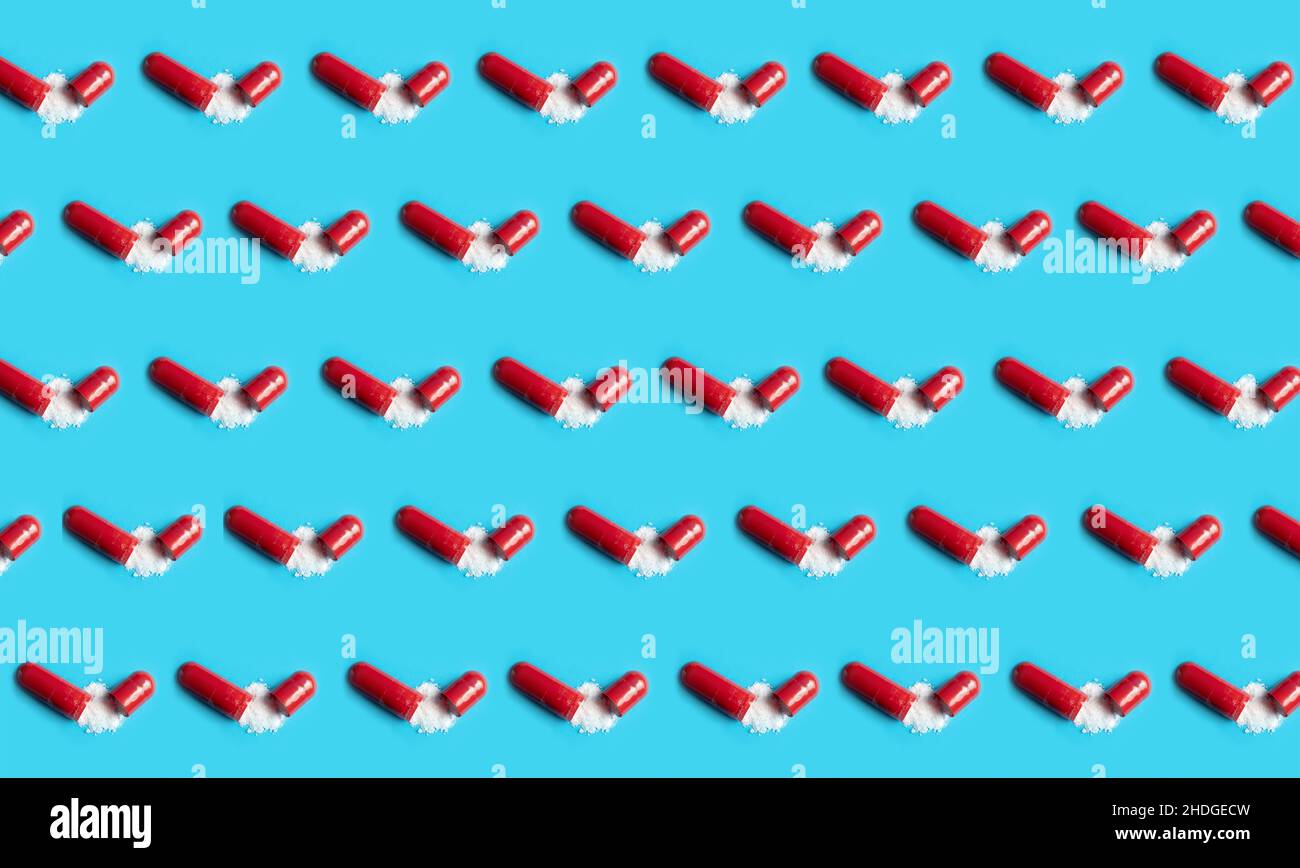 Lot of opened red gel capsules with white powder on blue background