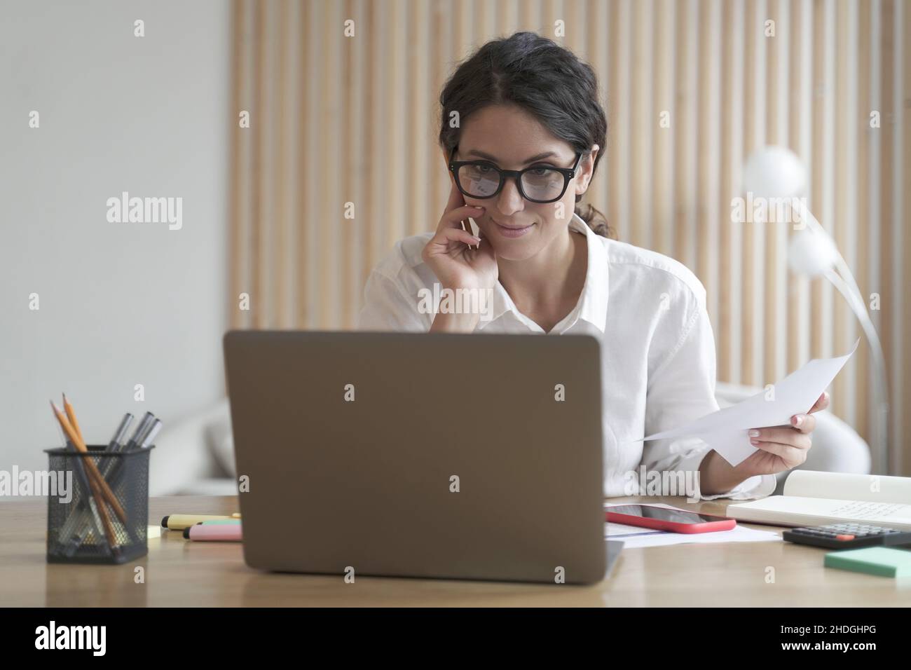Smiling confident business woman works on computer at home, consulting clients distantly online Stock Photo