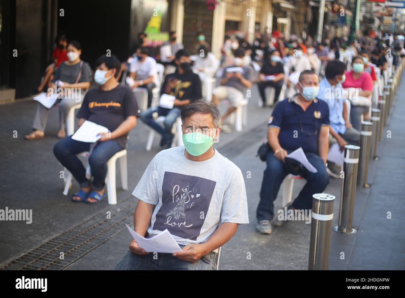 People sit and wait in a social distance queue to be tested for ...