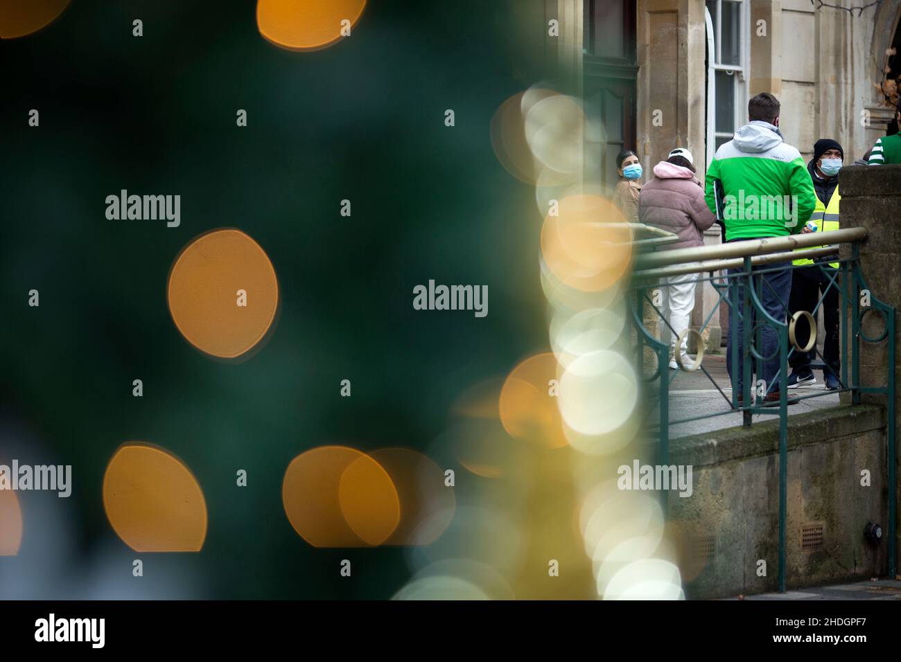 Members of the staff check people queuing outside a vaccination centre behind Christmas decorations on Christmas Day in London. Stock Photo