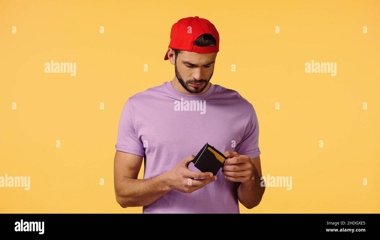 upset man holding empty wallet isolated on yellow Stock Photo