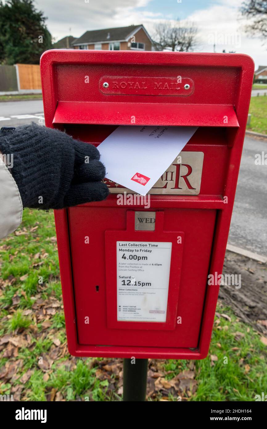 Posting first class letter in royal mail letter box 2021 Stock Photo