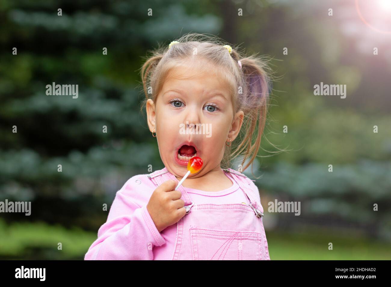Beautiful child with funny face licking lollipop Stock Photo