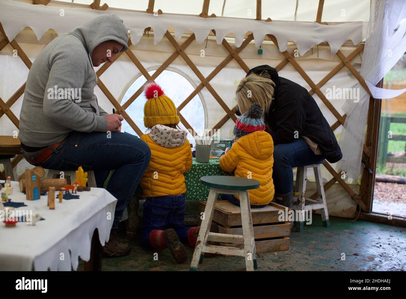 A family doing an activity inside a yurt with their two children, UK Stock Photo