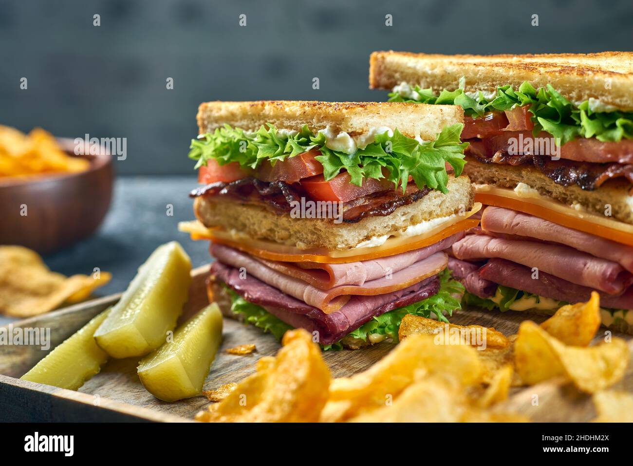 Pieces of club sandwich with potato chips on wooden tray Stock Photo