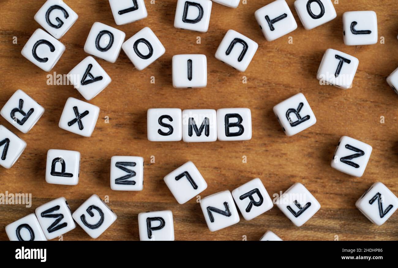 Tiny white and black bead cubes on wooden board, letters in middle spell SMB for Small to medium business Stock Photo