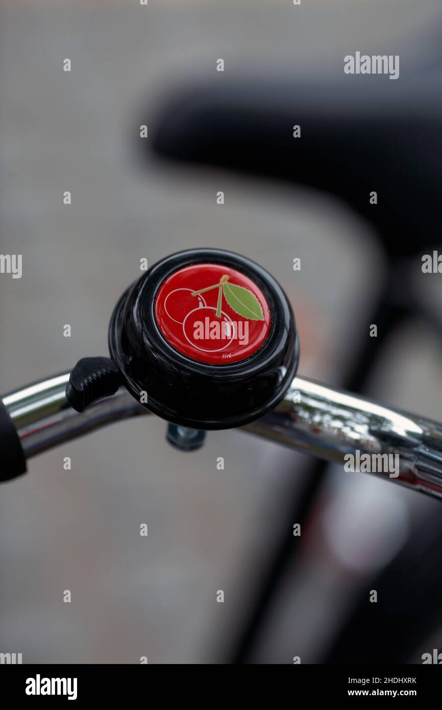 Cherry bicycle bell .Bicycle handlebar with bell with blurred background. Stock Photo