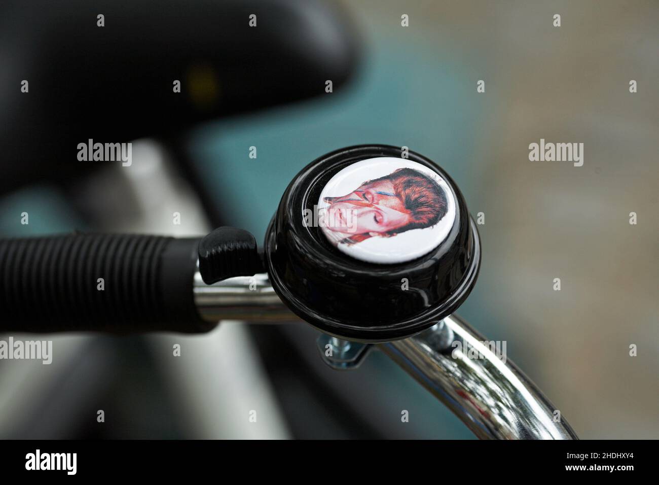 David Bowie – Ziggy Stardust bicycle bell .Bicycle handlebar with bell with blurred background. Stock Photo