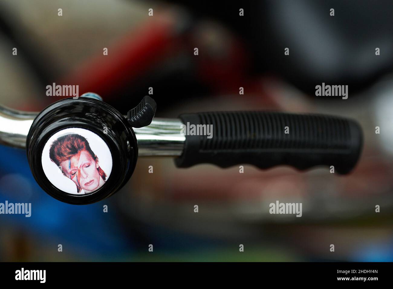 David Bowie – Ziggy Stardust bicycle bell .Bicycle handlebar with bell with blurred background. Stock Photo
