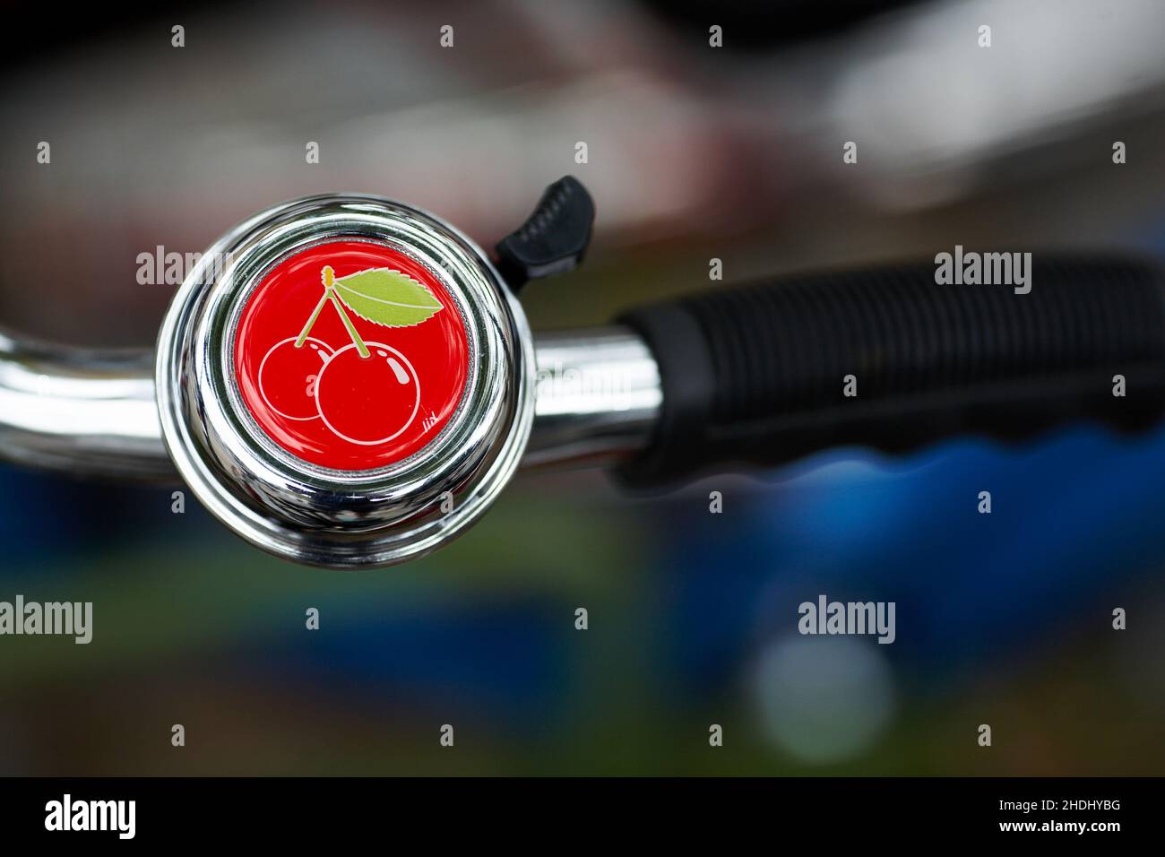 Cherry bicycle bell .Bicycle handlebar with bell with blurred background. Stock Photo