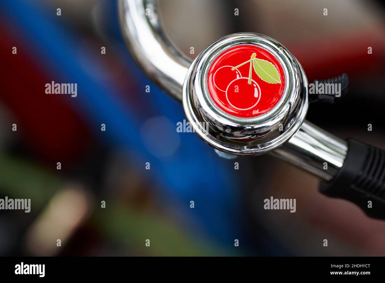 Cherry bicycle bell .Bicycle handlebar with bell with blurred background. Stock Photo