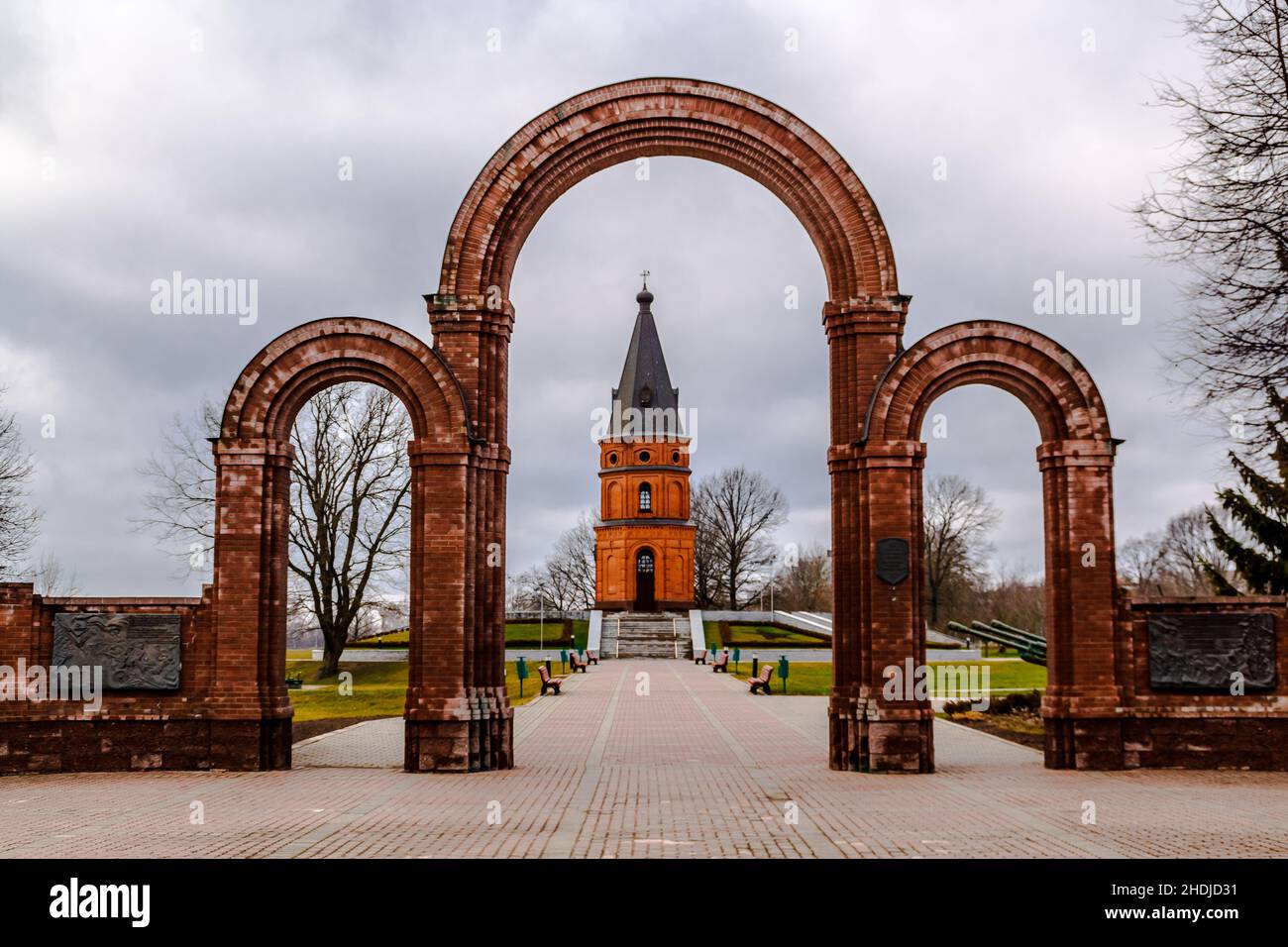 Buynichskoe field WWII memorial. Mogilev, Belarus - 28 November 2021: Gates of the memorial complex and brick red church. Stock Photo