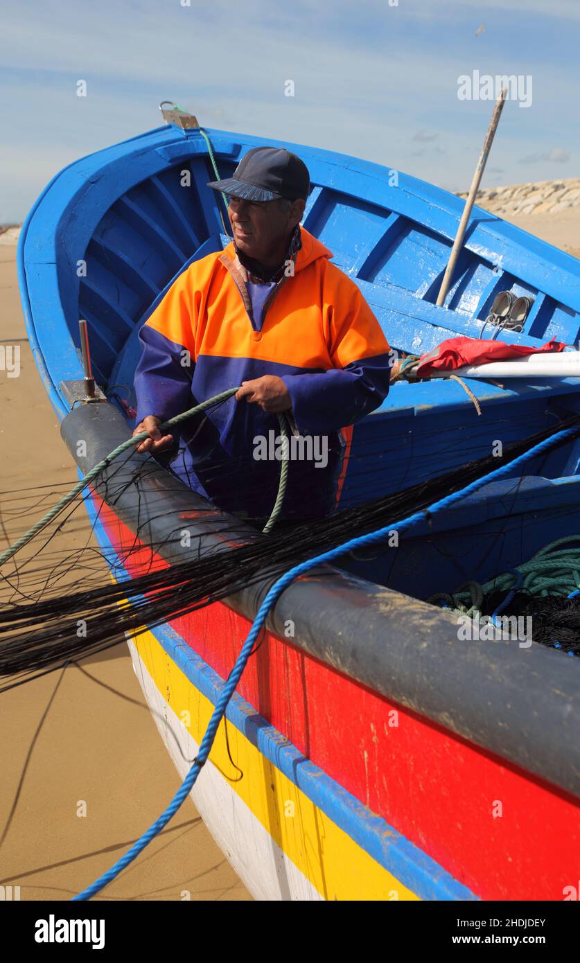 A coastal fisherman from the port of Traferia, on the Tagus River estuary, pull nets onto the beach at Caparica, on the Atlantic Coast of Portugal. Stock Photo