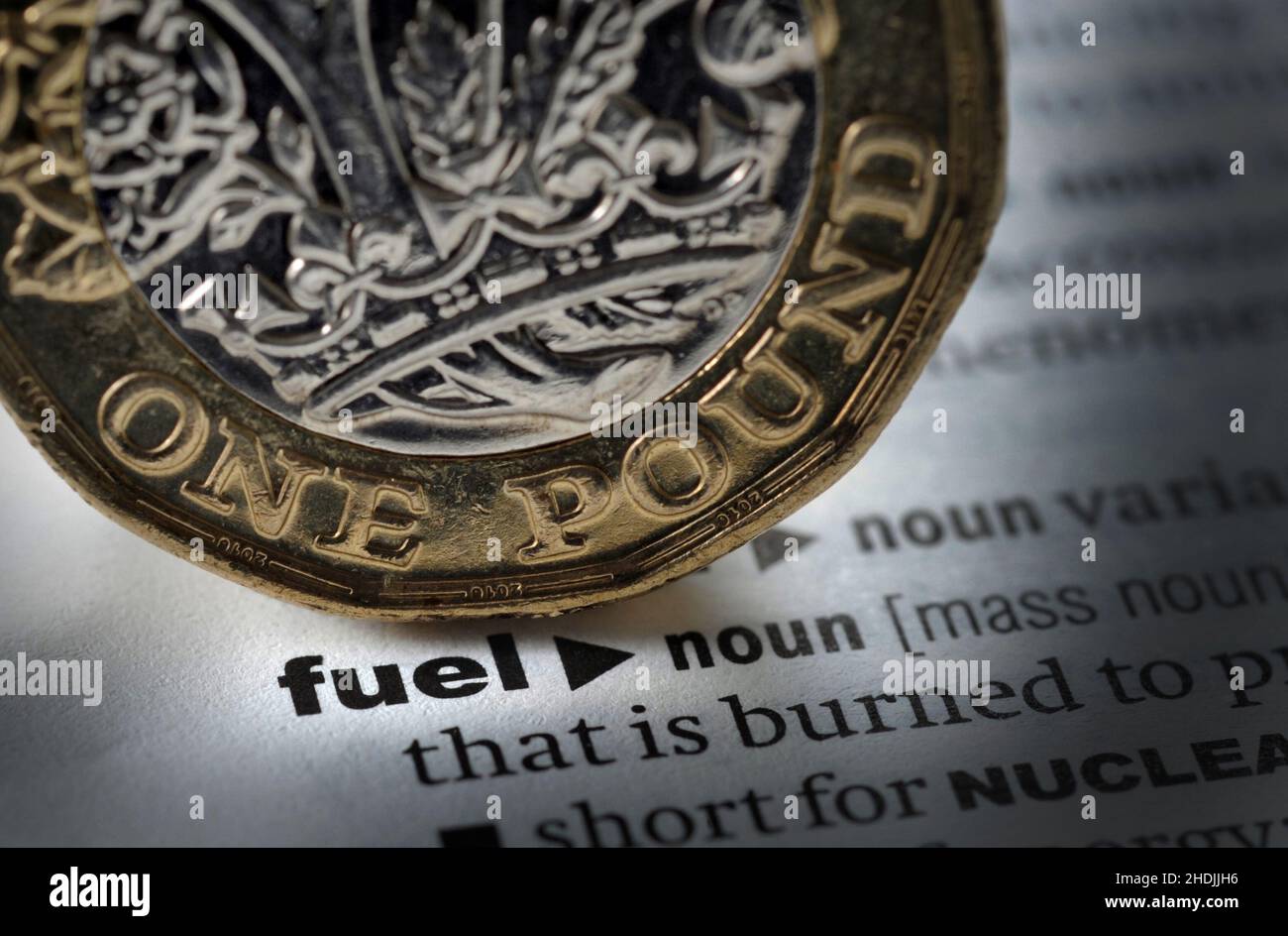 DICTIONARY DEFINITION OF WORD FUEL WITH ONE POUND COIN RE ENERGY RISING COSTS HEATING PETROL DIESEL FOSSIL FUELS EMISSIONS ETC UK Stock Photo