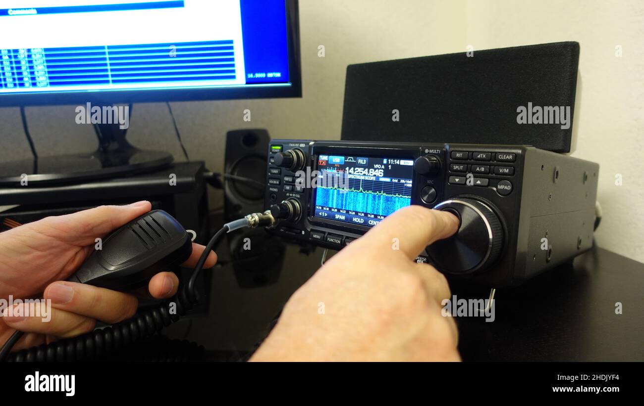 Man holding a microphone while operating an amateur radio. Stock Photo