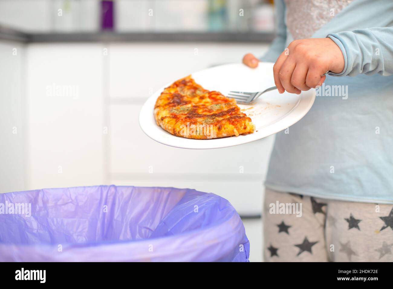 Child throwing food at garbage bin Stock Photo