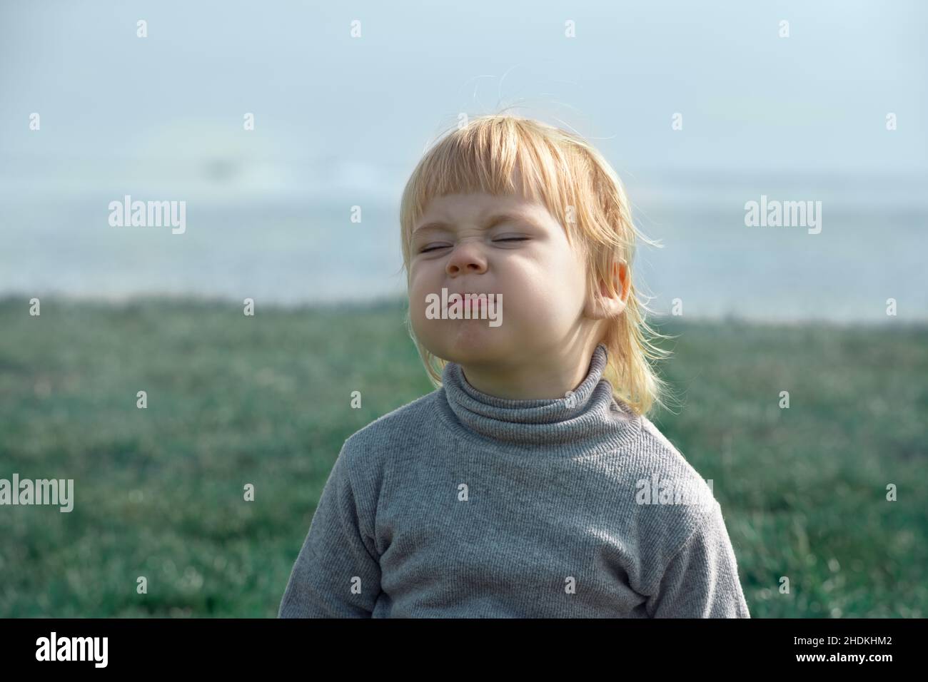 Child wrinkles face expressing dissatisfaction, face portrait Stock Photo