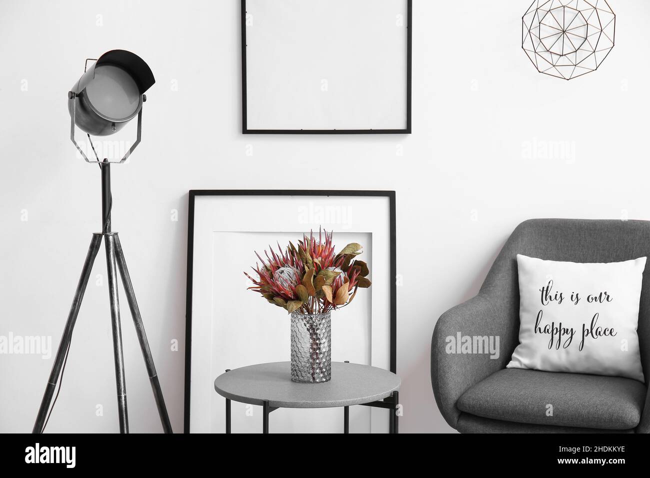 Closeup of stylish interior with lamp, blank picture frames, coffee