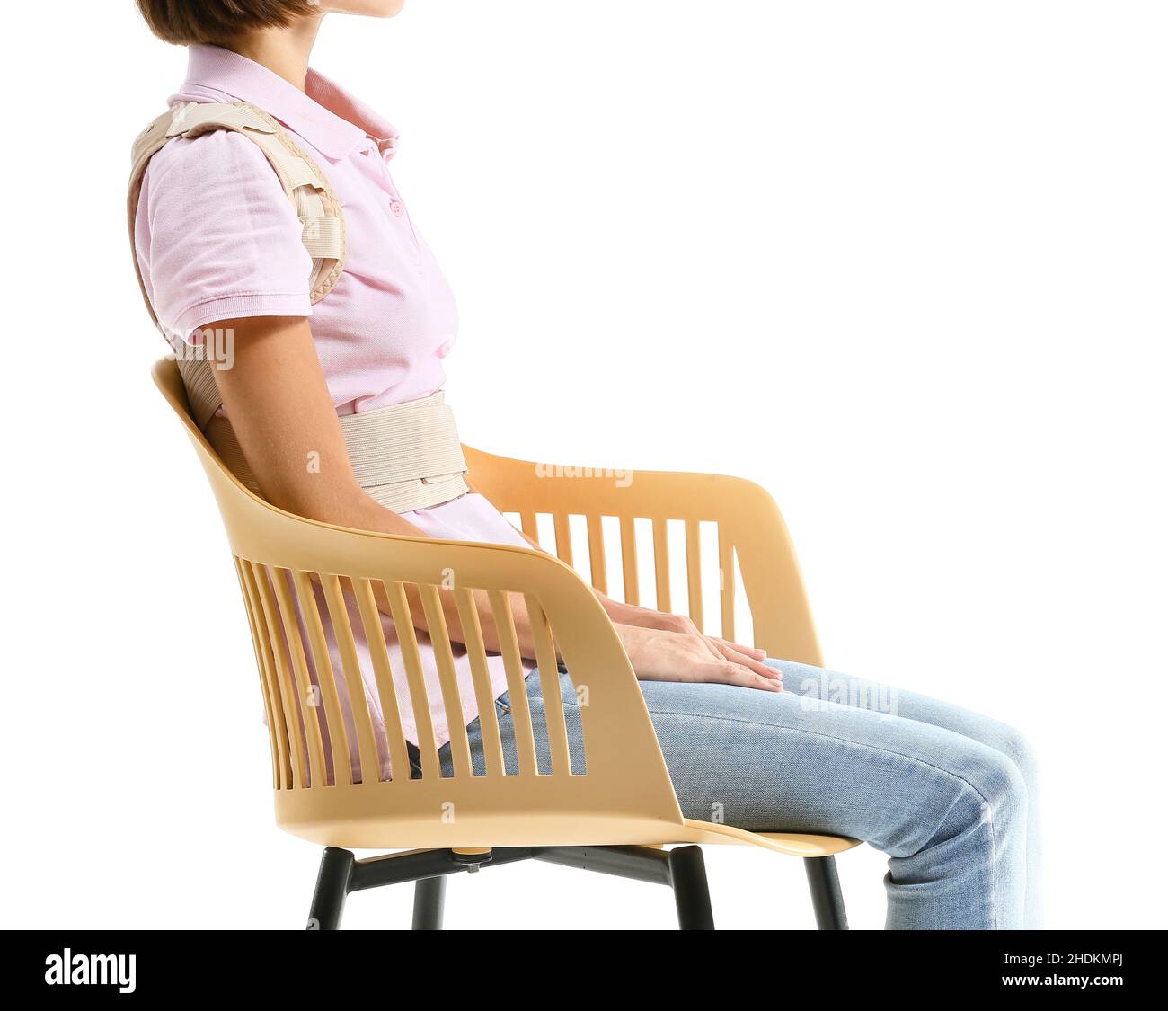 Young woman in back brace sitting on chair against white background