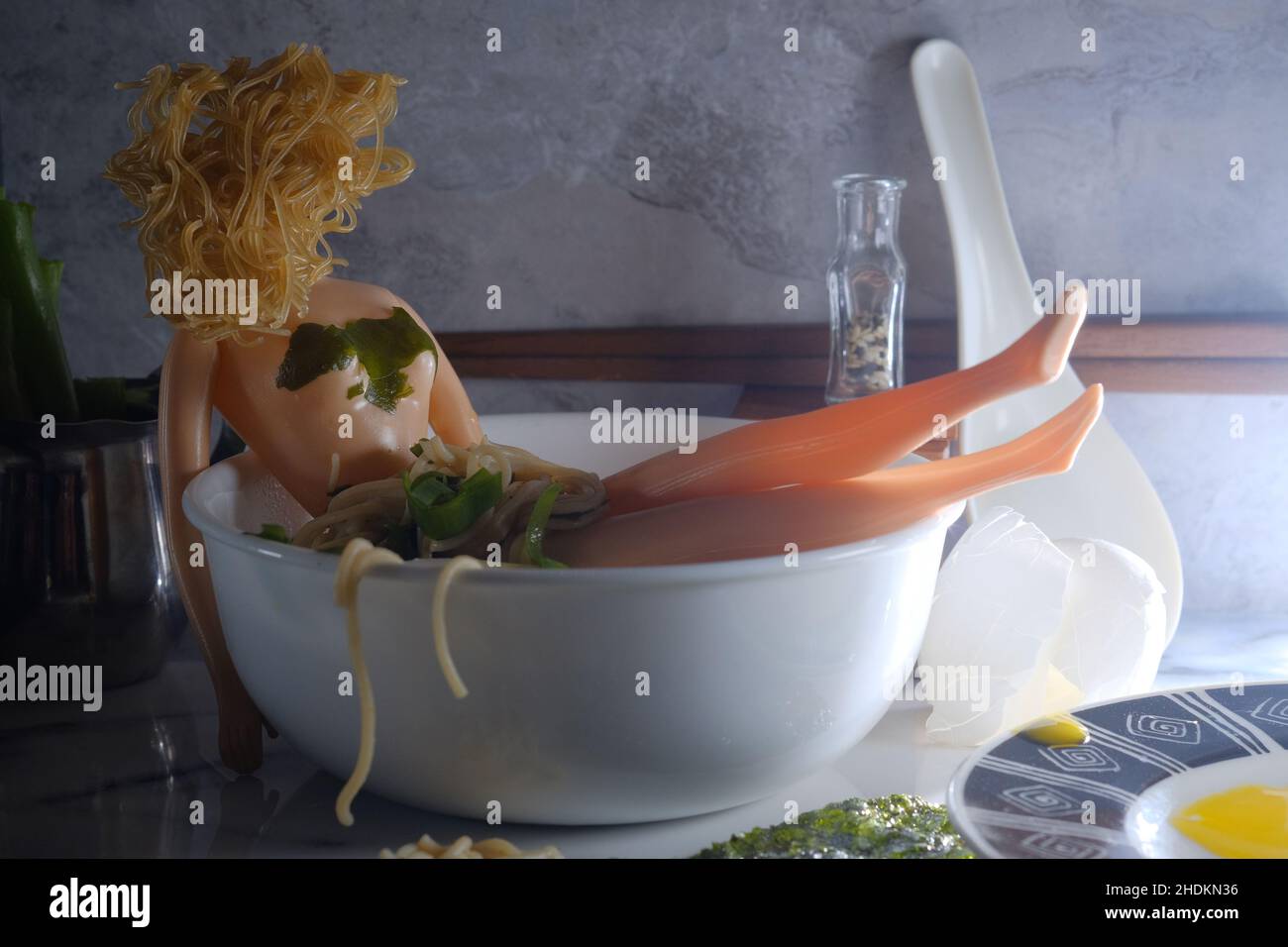 Relaxed doll bathes in Japanese ramen noodles concept Stock Photo
