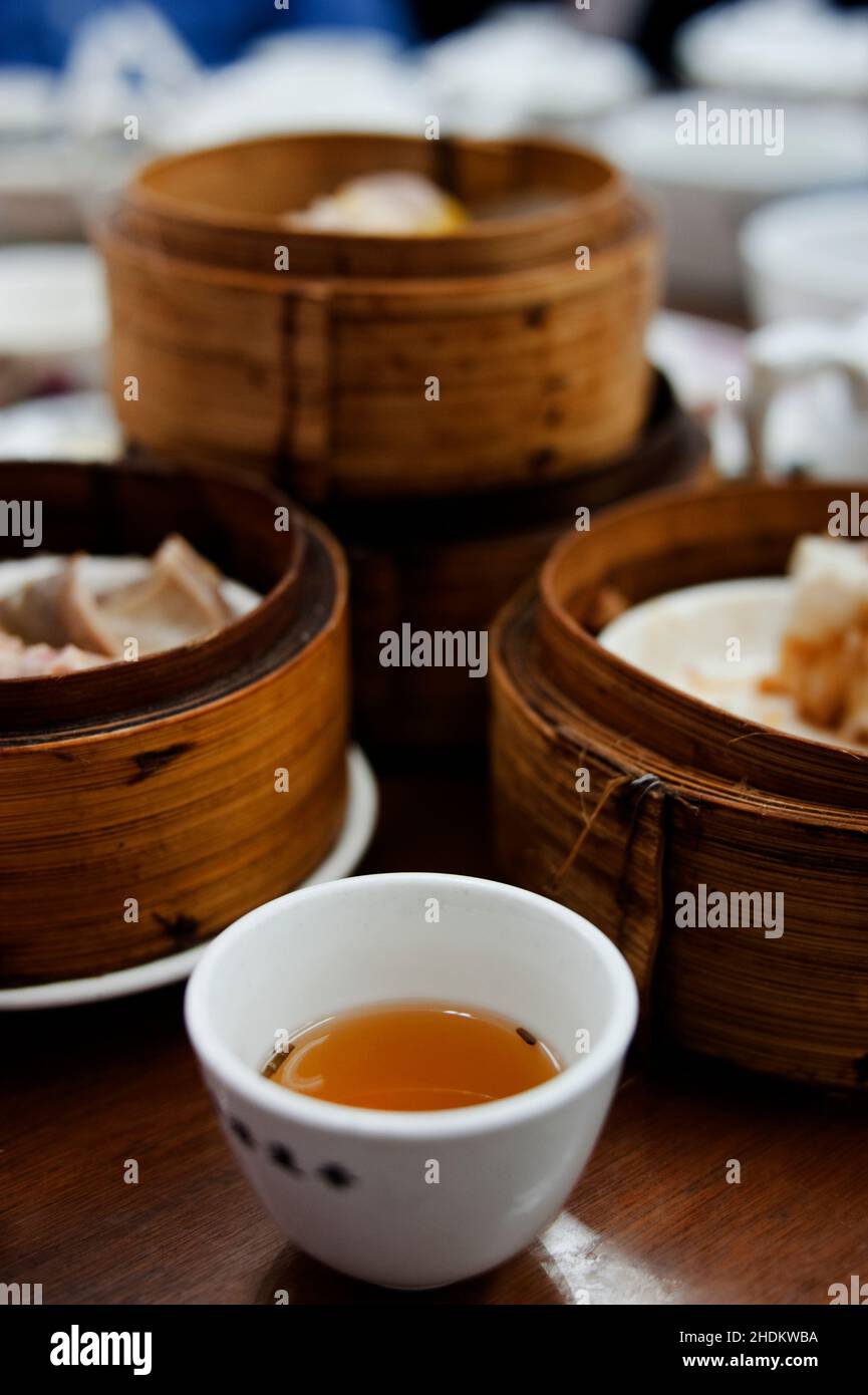 A cup of tea sits in front of steamer baskets at Dim Sum, or Yum Cha, at Lin Heung Tea House, Hong Kong Stock Photo