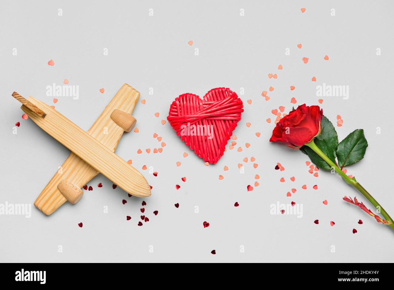 Wooden airplane, heart, rose and confetti on light background. Valentine's Day celebration Stock
