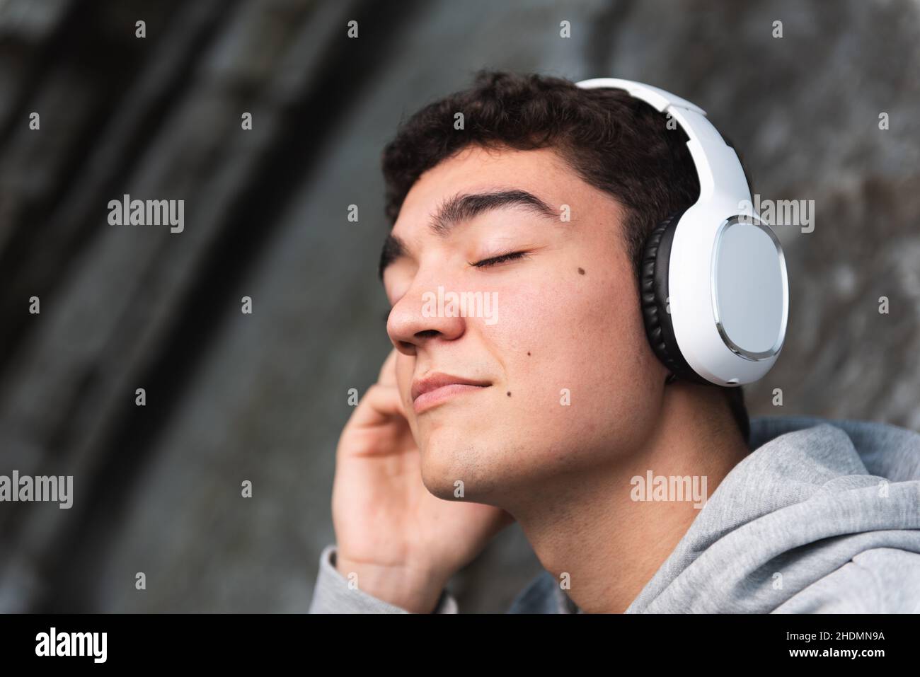 Portrait of hispanic teenager listening to music on headphones Stock Photo