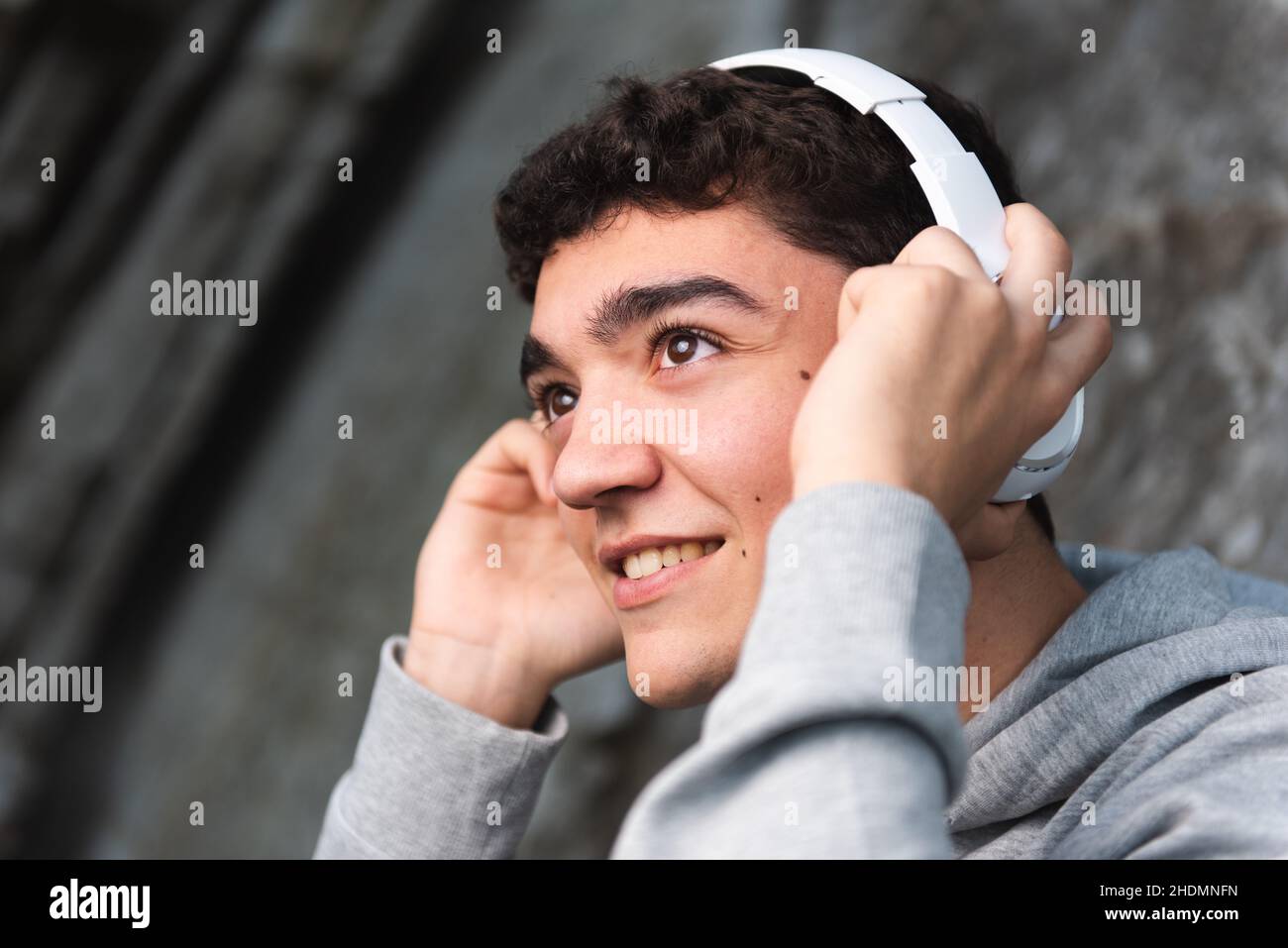 Happy hispanic teenager listening to music on headphones Stock Photo